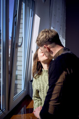 beautiful young couple kissing near the window