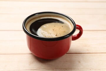 Cup of aromatic coffee on light wooden table, closeup