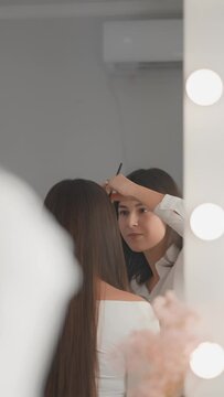 A vertical video in a beauty salon on makeup demonstrates the harmony of shapes and colors during a creative session female cosmetologist. She experiments, finding perfect combination for best effect.