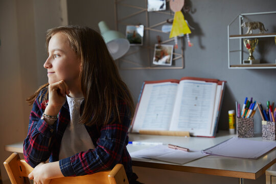 Kind tr&auml;umt beim Hausaufgaben machen aus dem Fenster, M&uuml;nchen, Bayern, Deutschland