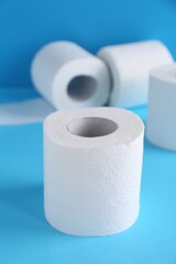 Soft toilet paper rolls on light blue background, closeup