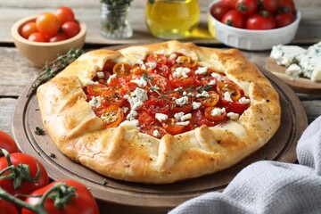 Tasty galette with tomato, thyme and cheese (Caprese galette) on wooden table, closeup