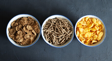 Diversi tipi di cereali da colazione secchi in ciotole isolate su sfondo grigio. Vista dall'alto....