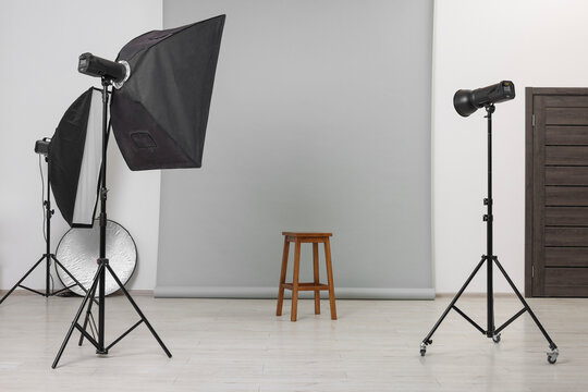 Empty stool surrounded by professional lighting equipment in photo studio