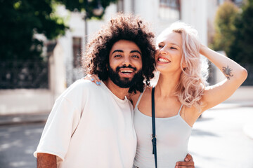 Fototapeta premium Smiling beautiful woman and her handsome boyfriend. Woman in casual summer jeans clothes. Happy cheerful family. Female having fun. Sexy couple posing in the street at sunny day. Embracing each other
