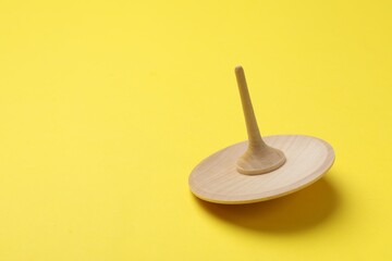 One wooden spinning top on yellow background, space for text