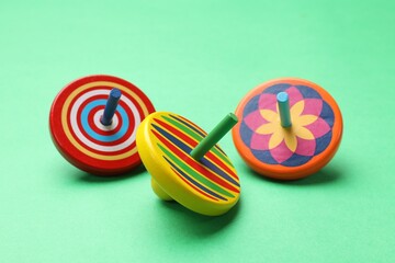 Many colorful spinning tops on green background, closeup