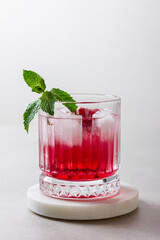 Raspberry cocktail with ice in a glass on a light background