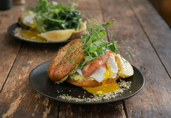 Tasty sandwich with avocado, salad and poached egg on a plate, close up, selective focus. Brunch on a rustic table.