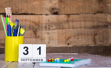 September calendar background with number  31. Stationery pens and pencils in a case on a wooden...