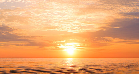 Sunset sky background over sea in the evening with beautiful yellow sunlight reflection on water surface in golden hour time