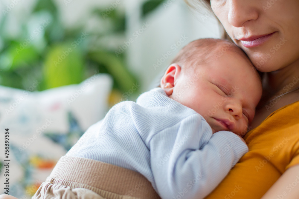 Wall mural Young mother, holding tenderly her newborn baby boy