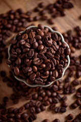 Coffee beans into bowl on white table. Top view. Soft focus