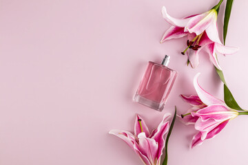 Transparent bottle of women's perfume or on pastel background with garden delicate lilies. Presentation of a floral fragrance. Top view. A copy space.