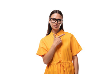 a black-haired slender woman dressed in an orange dress attracts attention pointing to the side with her hand