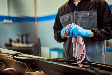 Photo of a mechanic's hands, wearing protective gloves, using a cloth, and cleaning hands. - 756407587