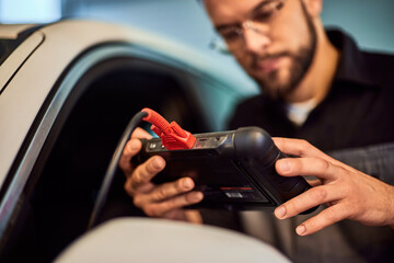 Focus on the mechanic's hands, holding a digital tablet, doing diagnostics on the car. - 756408535
