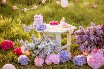 Summer outdoor kids birthday party background. Celebrating birthday in park. Kids party pink pastel decoration and food. Presents and sweets.