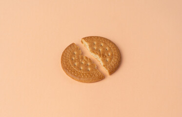 two halves of Maria biscuit on a pink beige background. 