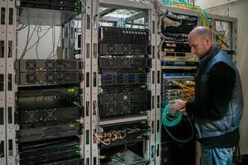 A technician works with patch wires in the server room of a data center. Man supports the technical platform of the Internet provider.