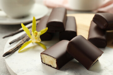 Glazed curd cheese bars, vanilla pods and flower on board, closeup