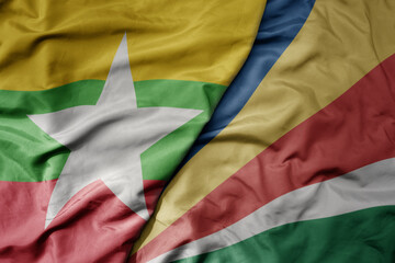 big waving national colorful flag of seychelles and national flag of myanmar .