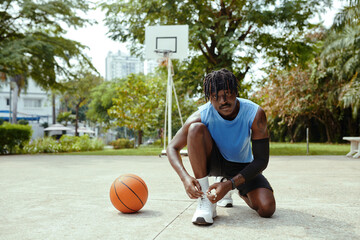 Black streetball player tying shoe laces when getting ready for game