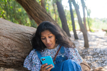 Young indian woman using mobile phone in the countryside 