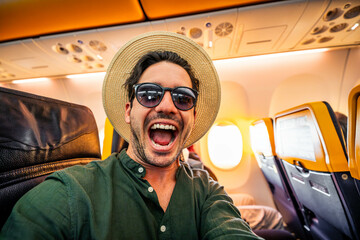 Happy young tourist taking selfie picture on a plane

