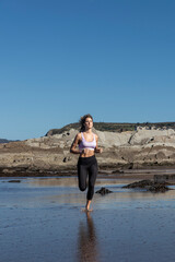 woman runs on a beach with a blue sky in the background. Concept of freedom and relaxation, as the woman enjoys her run in a beautiful natural setting