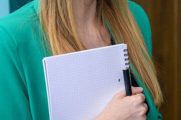 Młoda dziewczyna trzyma zeszyt na notatki i pióro do pisania w rękach  - obrazy, fototapety, plakaty