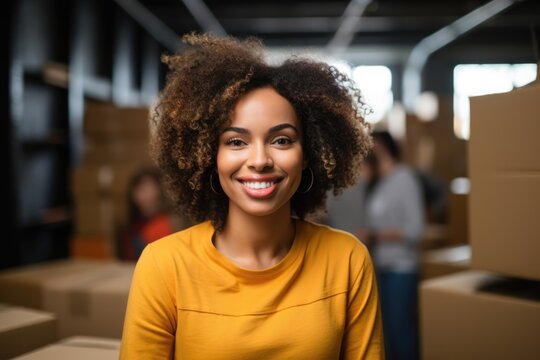 Smiling Woman Standing in Room Full of Boxes looking at camera.