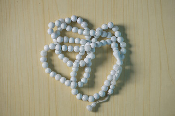 Prayer beads white for Ramadan, isolated on a wood background