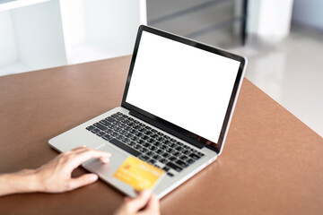 Woman shopping online using laptop holding a credit card at the home. Mock up laptop