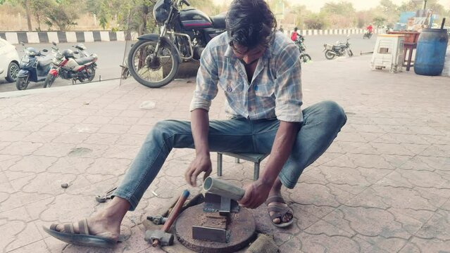 Artisan sharpening tools on a grinding wheel at a street workshop in india