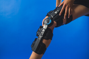 woman fitting a knee brace with angle movement controler over blue background. High quality photo - Powered by Adobe