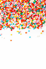 Colorful confectionery sprinkles border on white background. Copy space for text. Top view