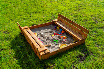A square-shaped playground made of a wooden closed box, the box is open.