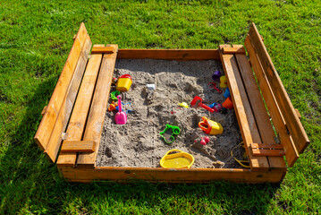 A square-shaped playground made of a wooden closed box, the box is open.