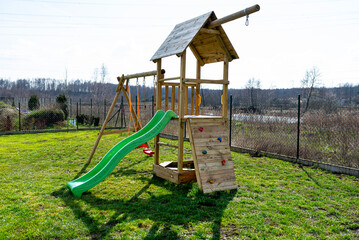 A childrens playground in the garden is made of unpainted wood.