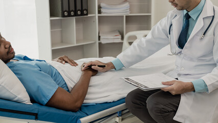 Doctor talking with patient in hospital, male patient lying in bed and doctor providing care,...