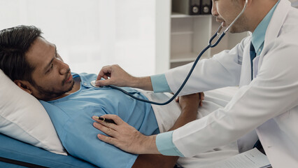 Asian male doctor holding stethoscope and listening to patient Doctor doing heart check examining...