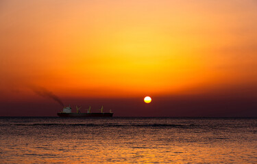 Bright sunset with a big yellow sun under the sea surface.