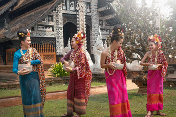 Fototapeta na wymiar Group of Beautiful Lanna Asian woman wearing Thai costumes having fun splashing water to each other on Songkran festival. 