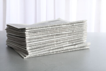 Stack of newspapers on light grey table. Journalist's work