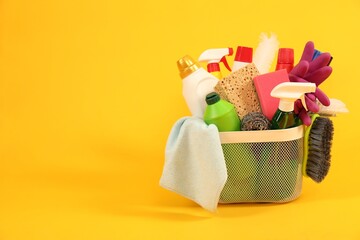 Different cleaning products in basket on yellow background, space for text