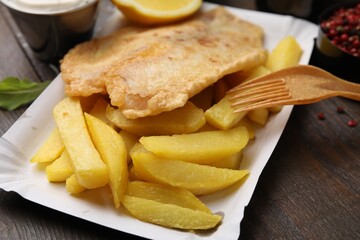 Delicious fish and chips served on wooden table, closeup