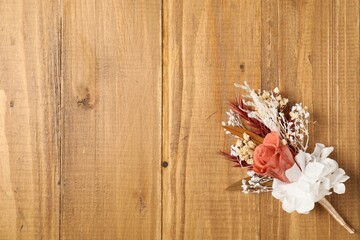Stylish boutonniere on wooden table, top view. Space for text