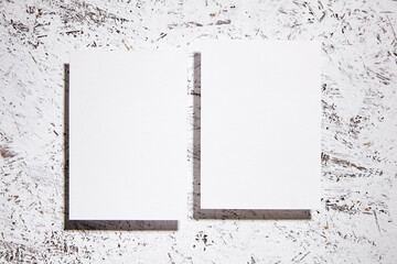 Blank white cards mockup against a white textured background with black paint splatters, top view, flat lay