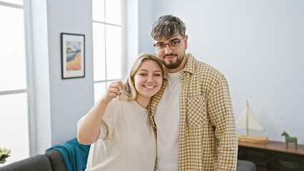 A happy couple holds house keys in a bright living room, symbolizing new homeownership and starting together.